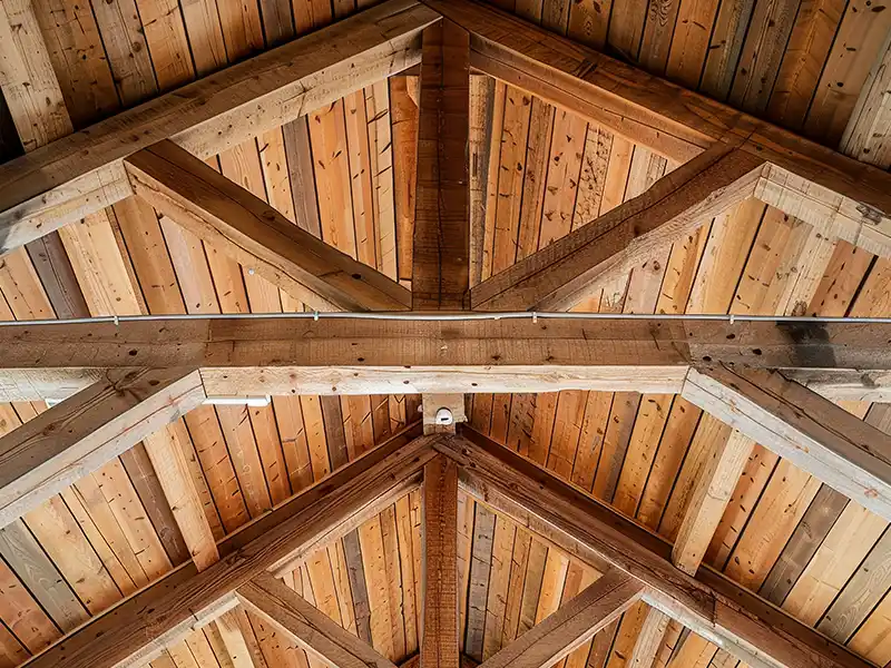 Traitement de charpente dans le Gard - Rénovation Sud Vue rapprochée d'un plafond voûté en bois avec des poutres apparentes disposées de manière symétrique, mettant en valeur le grain naturel et la texture du bois, souvent entretenus avec le traitement de charpente dans le Gard.